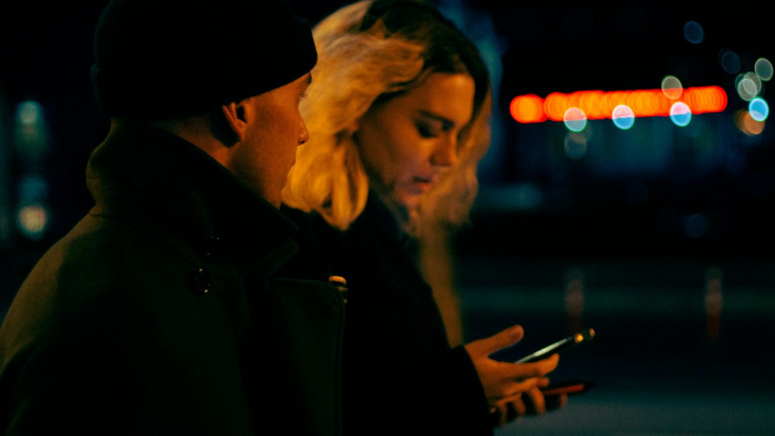 a man and woman looking at a cell phone