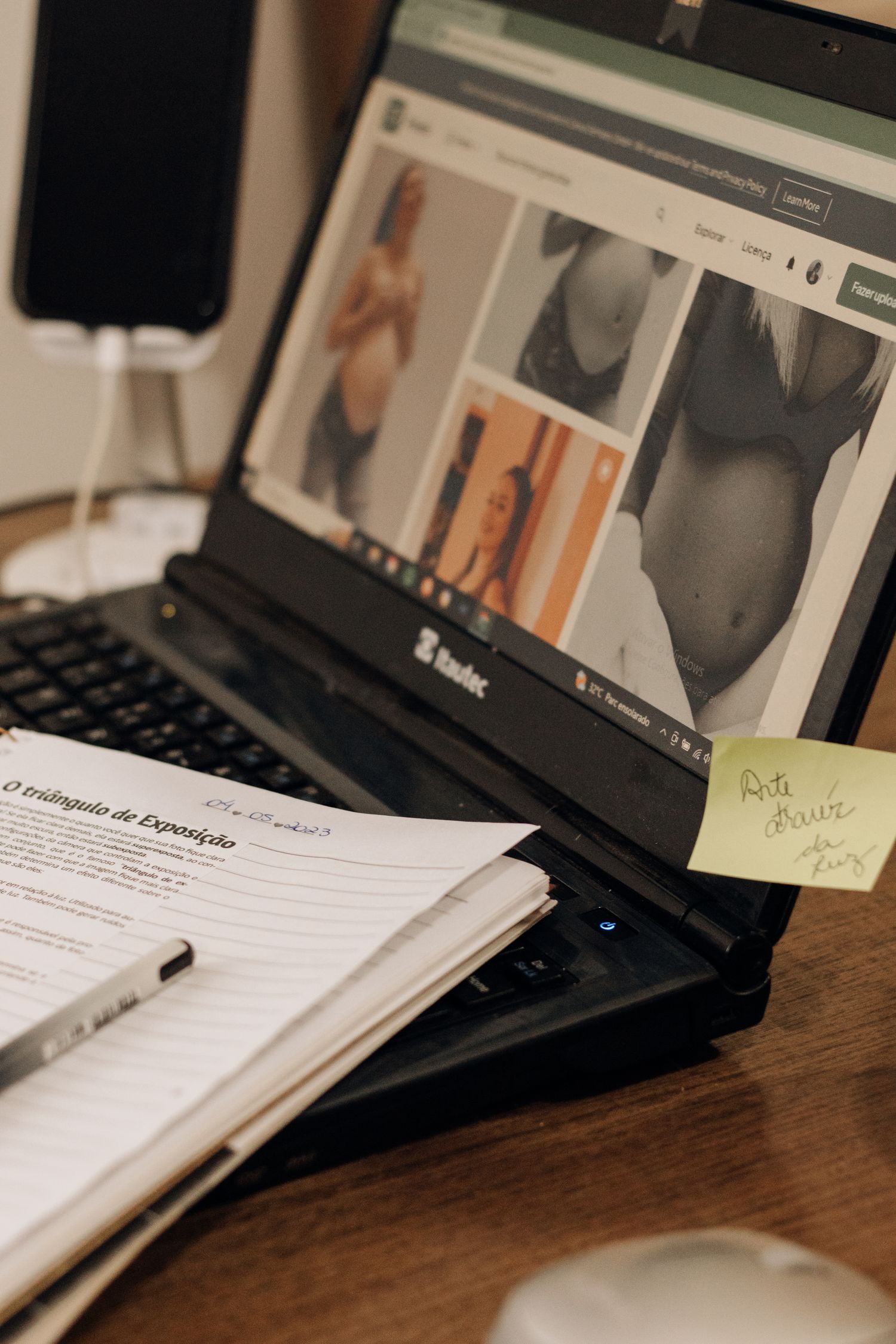 Close-up of laptop, notepad, and documents on desk with pregnancy images.