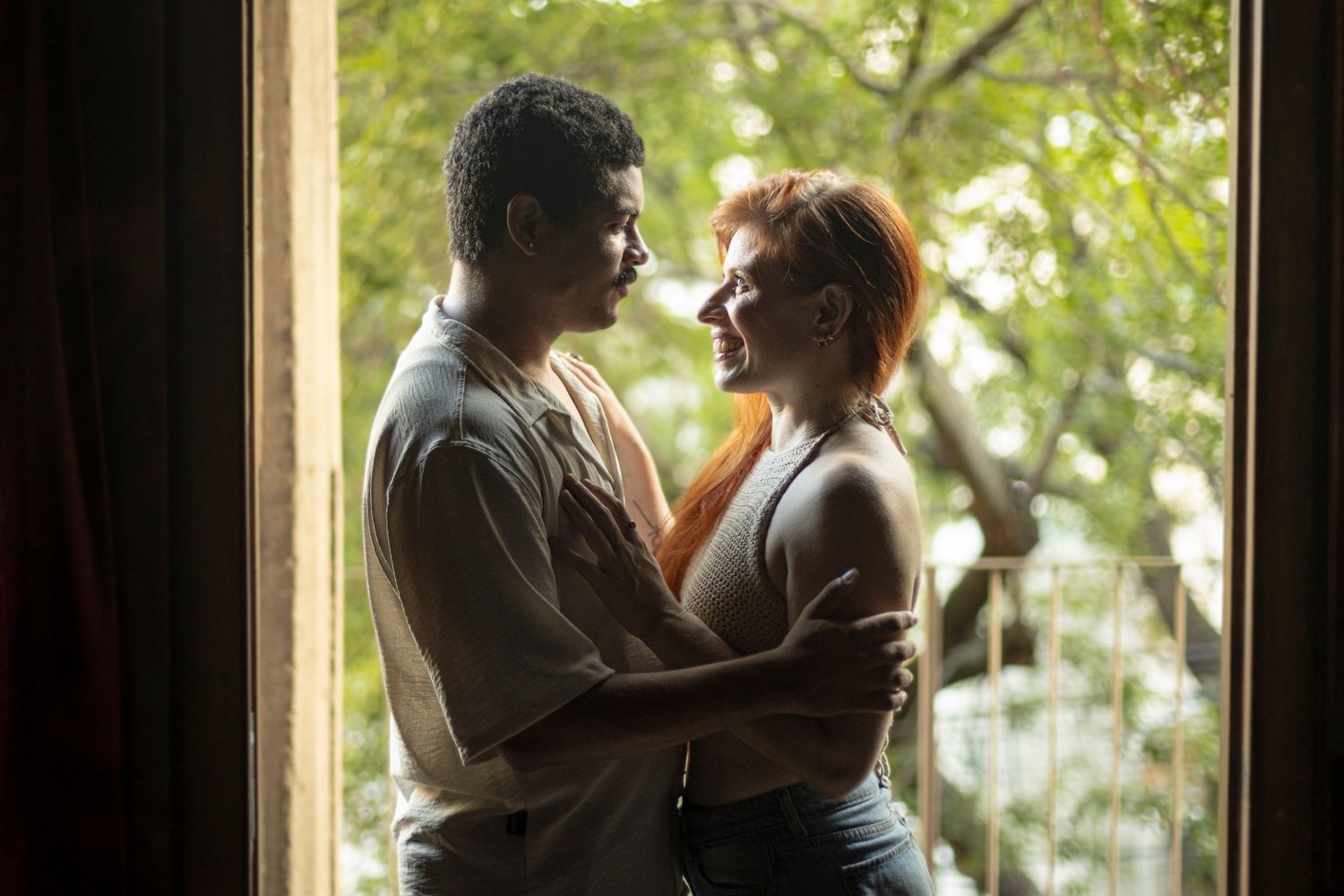 A loving couple sharing a tender moment by a doorway with natural light flowing in. Captured in Buenos Aires.