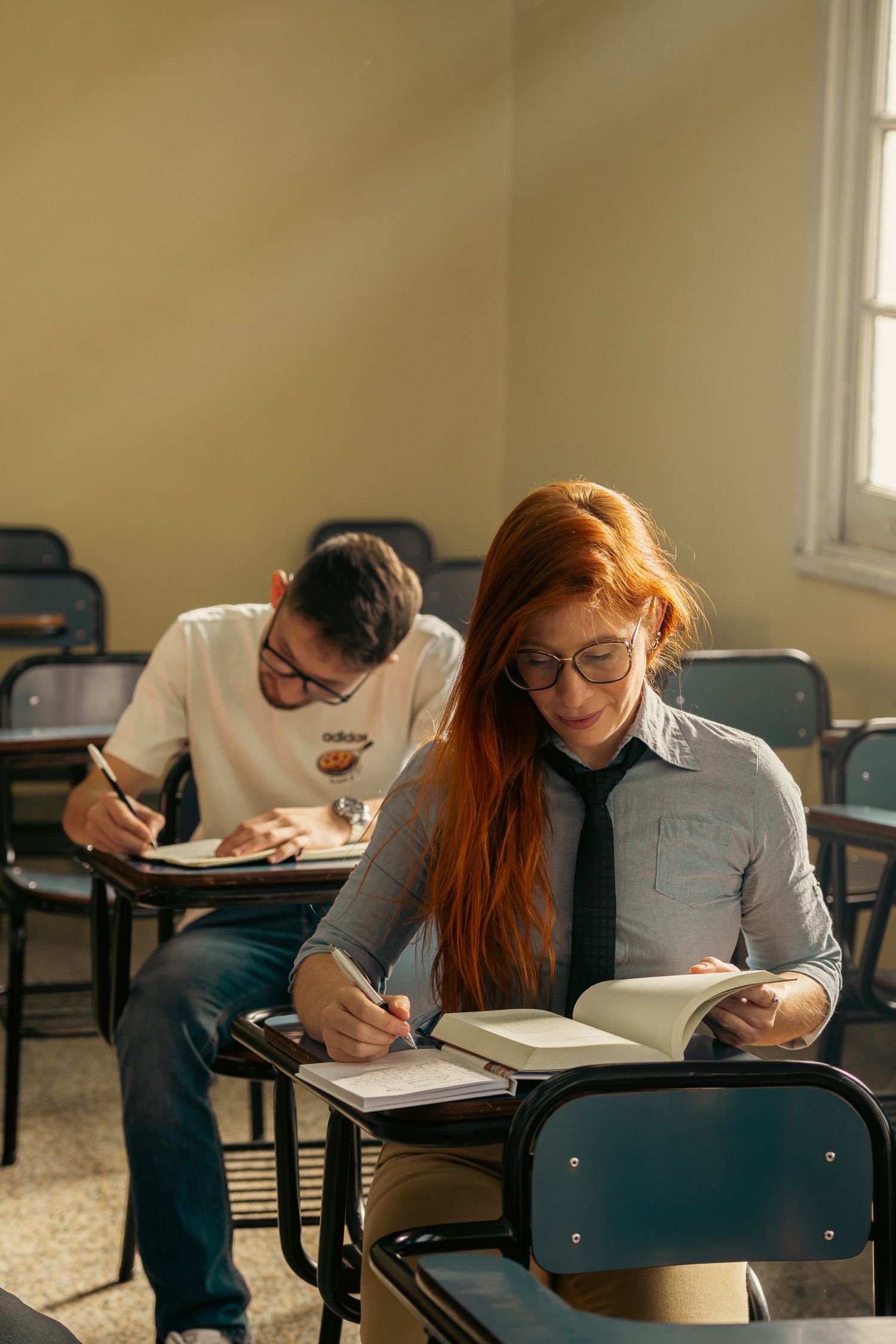 Two students intensely focused on their studies inside an educational classroom setting.