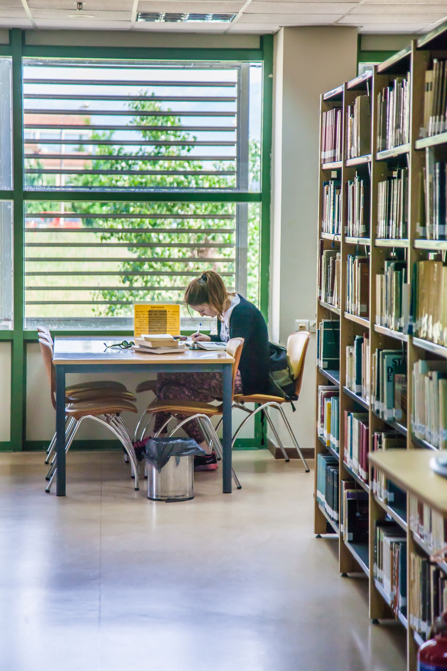 A person studies alone in a library surrounded by shelves full of books.