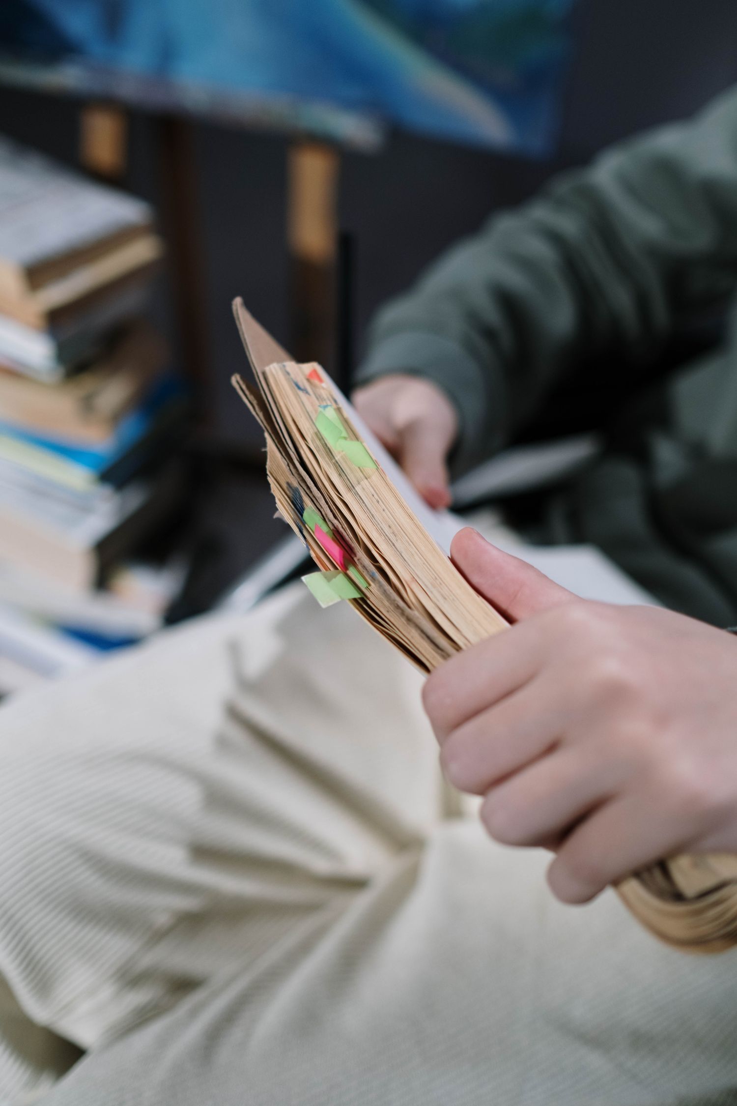 Close-up of hands holding a well-tabbed book in a cozy indoor setting, emphasizing study and relaxation.