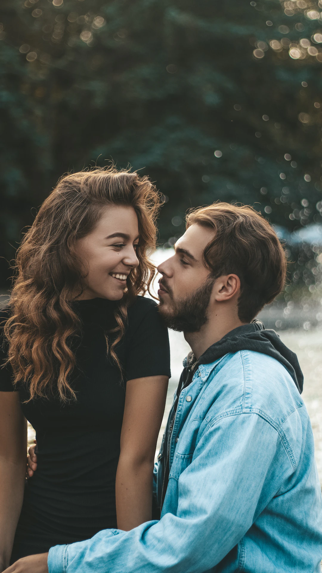 woman in black shirt kissing woman in blue denim jacket during daytime